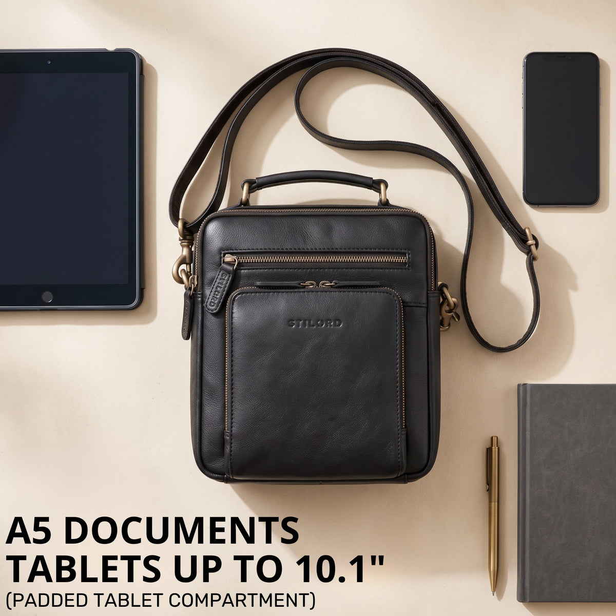 Small black leather shoulder bag with top handle and embossed STILORD logo, front pocket; tablet and phone beside it