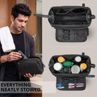 Black leather toiletry bag with wide-open main compartment, internal dividers, elastic loops and zip pocket; man placing a tube