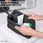 Leather toiletry bag black with wide opening, interior view showing hands and toiletry items on a towel, STILORD embossing visible